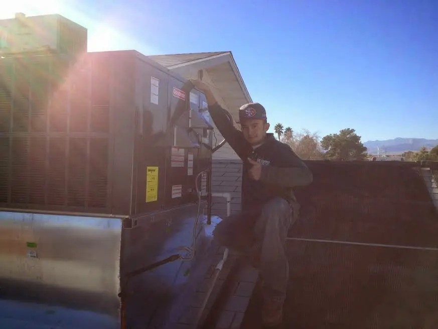 HVAC technician performing AC Tune-Up on a rooftop unit in Corona de Tucson